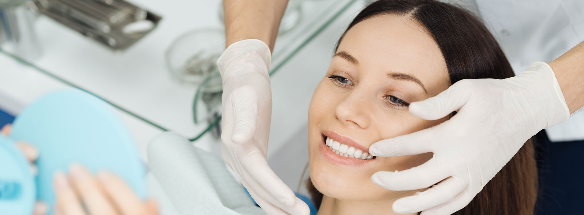 The image depicts a woman receiving a facial treatment with a mask on her face, being attended to by a professional who appears to be applying a product, while wearing medical gloves and a surgical mask.